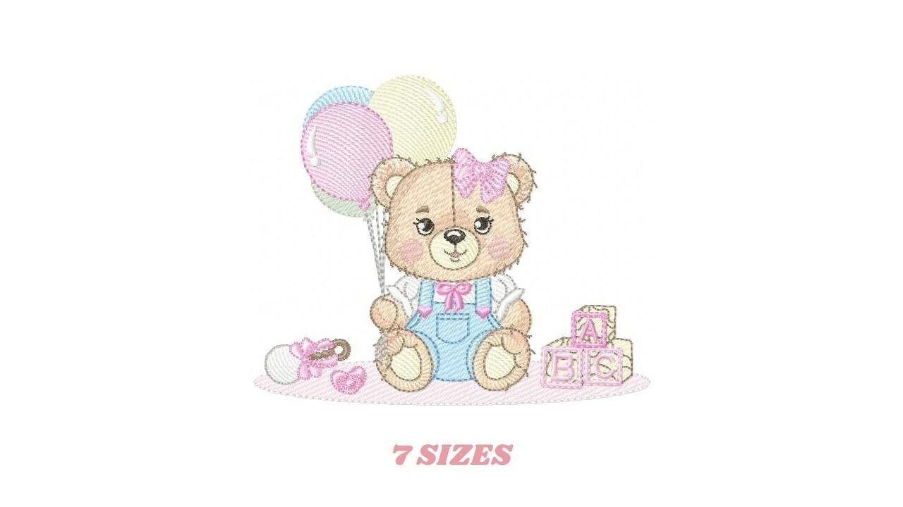 May include: Embroidered design of a brown teddy bear wearing a blue overall and a pink bow. The bear is holding three balloons in pink, yellow, and blue. The bear is sitting on a pink surface with a pink pacifier and a block that says "ABC" in pink.