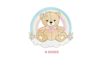 May include: Embroidered design of a brown teddy bear sitting on a cloud with a rainbow behind it. The bear has a pink bow and flowers on its head. The design is surrounded by flowers.
