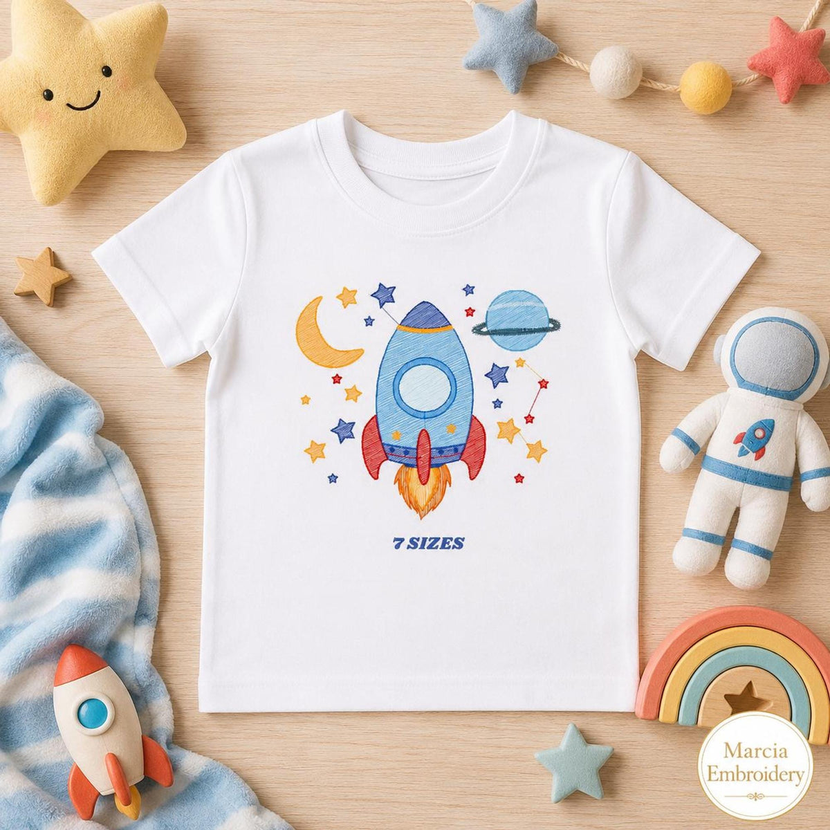 White toddler tee with playful rocket ship embroidery design, blue rocket, stars, moon
