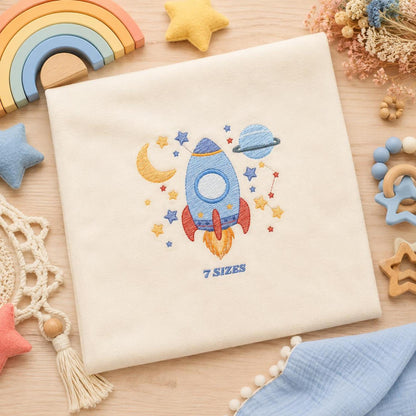 Beige baby bodysuit styled with rocket ship embroidery design, soft toys and rainbow props