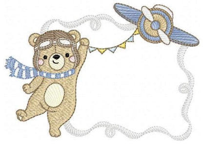 Closer view of aviator teddy bear embroidery, pilot goggles and striped blue scarf inside rippled frame