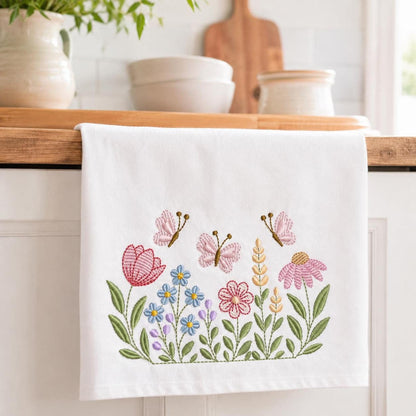 White kitchen towel draped over counter, colorful floral border with butterflies, embroidery designs for towels
