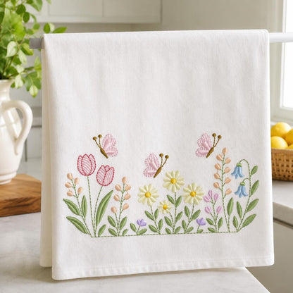Close-up towel fold showing pink tulips, yellow daisies, green leaves, garden embroidery design for linens